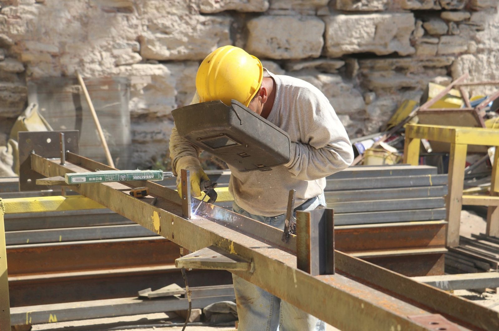 A worker checking a steel and timber assembly with a level.